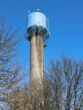 A brick water tower against the backdrop of sky and trees Stock Photos