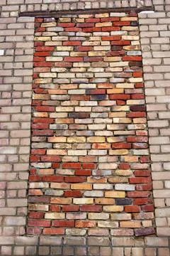 A bricked-up window opening in the brick wall of an old industrial building. Stock Photos
