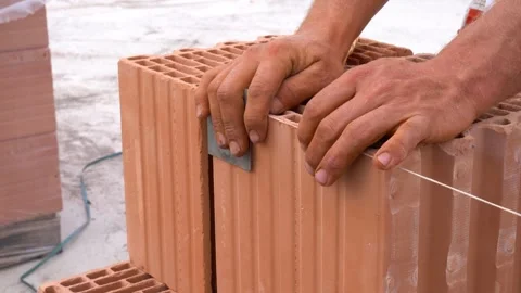 Bricklayer adjusting ceramic block with string during wall alignment Stock Footage 310356495