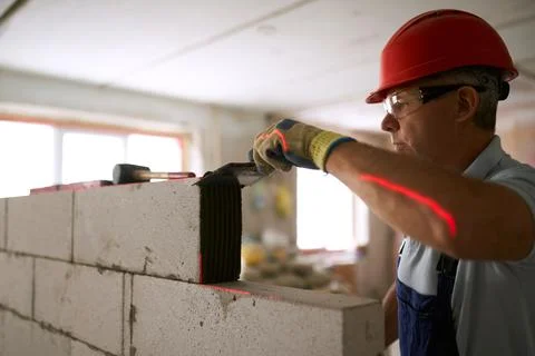 Bricklayer applies adhesive glue on autoclaved aerated concrete blocks with Stock Photos