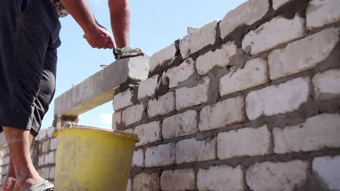 Bricklayer applying mortar to wall with trowel Stock Footage 310042814