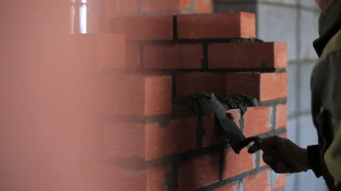Bricklayer applying mortar while building brick wall indoors Stock Footage 323433699