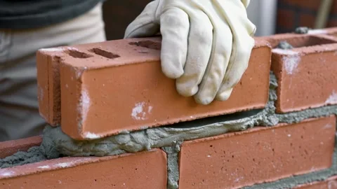 Bricklayer building house wall from red bricks, applying mortar Stock Footage 334779207