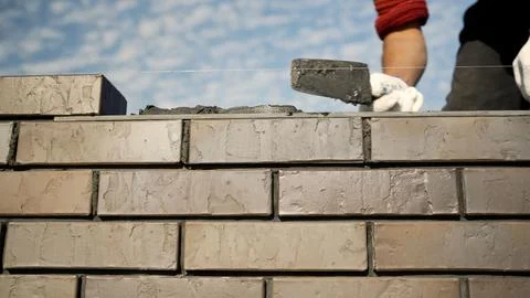 Bricklayer building a wall with bricks and mortar Foto stock
