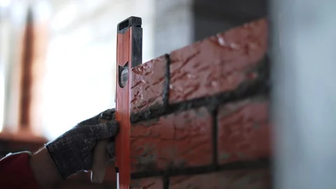 Bricklayer checking brick wall alignment with spirit level Stock Footage 323444786