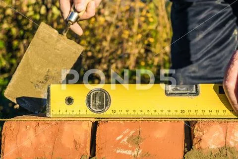 Bricklayer checks the horizontal level of brick masonry wall Stock Photos