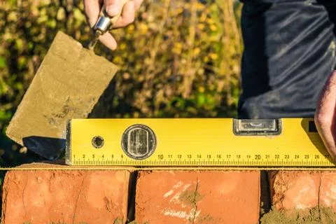 Bricklayer checks the horizontal level of brick masonry wall Stock Photos