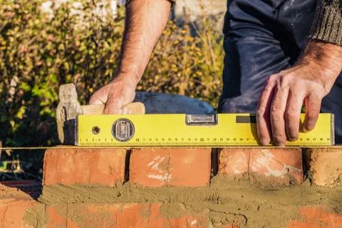 Bricklayer checks the horizontal level of brick masonry wall Stock Photos