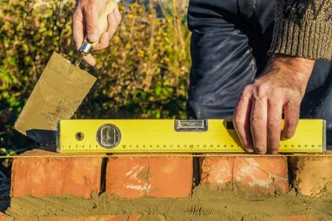 Bricklayer checks the horizontal level of brick masonry wall Stock Photos