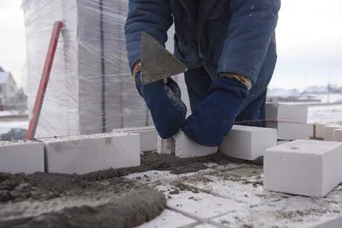 A bricklayer on a construction site puts bricks in cement. Stock Photos