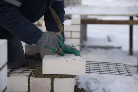 A bricklayer on a construction site puts bricks in cement. Stock Photos