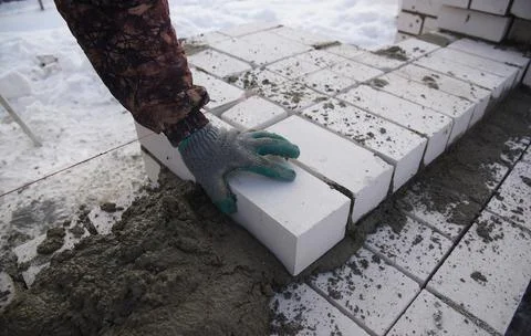 A bricklayer on a construction site puts bricks in cement. Stock Photos