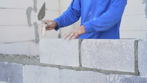 Bricklayer installing brick masonry building walls on construction site Stock Footage 262161482