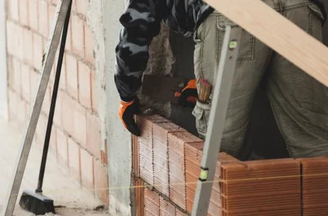 Bricklayer installing brick masonry on interior wall. Stock Photos