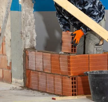 Bricklayer installing brick masonry on interior wall. Stock Photos