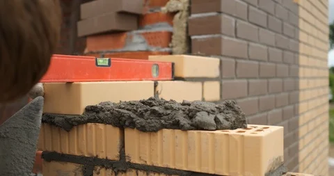 Bricklayer at large construction site work on building wall, uses level to check Stock Footage 118295944