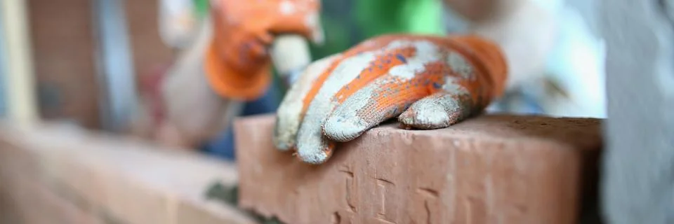 Bricklayer lays bricks on cement building exterior or interior walls Stock Photos