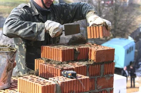 A bricklayer lays bricks to make a wall. Foto stock