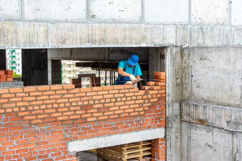 Bricklayer lays a partition during the construction of a frame monolithic str Foto stock