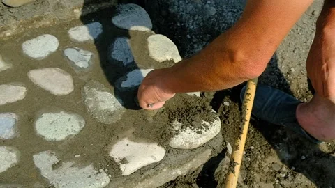 A bricklayer lays stones on a path. Video stock 134611319