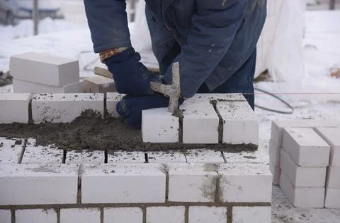 The bricklayer levels the bricks in the cement, makes a concrete wall. Stock Photos