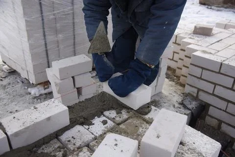 A bricklayer levels cement blocks, makes a concrete wall. Stock Photos