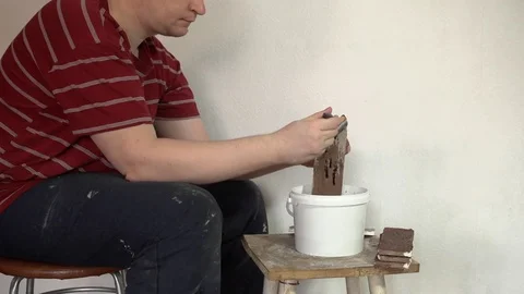Bricklayer makes a decorative brick, covering the workpieces with liquid paint Stock Footage 75518127
