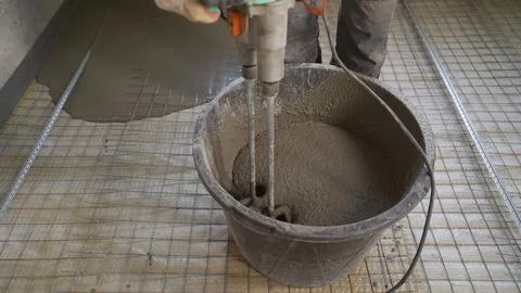 Bricklayer mixes cement in a bucket. The process of filling the floor with mo Stock Photos
