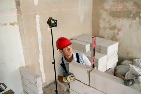 Bricklayer or mason lays bricks to construct wall of autoclaved aerated concrete Stock Photos