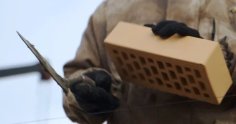 Bricklayer picks up brick and puts it in wall. Builder is building brick wall. Stock Footage 128939224