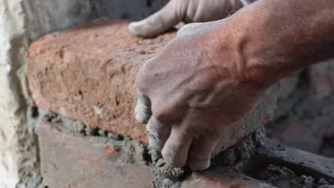 Bricklayer placing red brick Видео 332587584