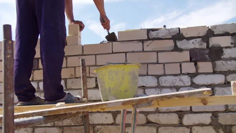 Bricklayer preparing mortar on scaffold for wall construction Stock Footage 310107592
