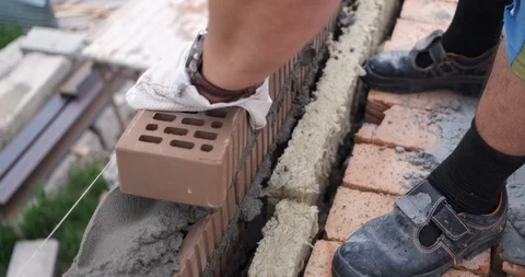 Bricklayer professionally and quickly spreads brick wall, levels mortar Stock Footage 116796046