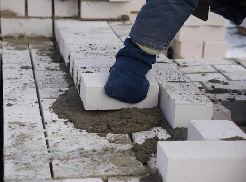 A bricklayer puts bricks in cement, close-up. Stock Photos