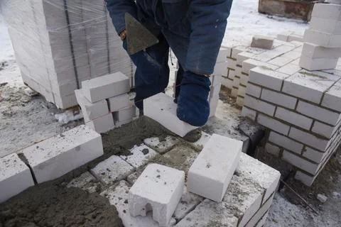 A bricklayer puts bricks in cement. Stock Photos