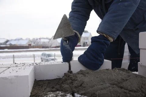 The bricklayer puts bricks in cement in straight rows, makes a concrete wall. Stock Photos