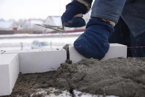 A bricklayer puts bricks in cement, works on the construction of a house. Stock Photos