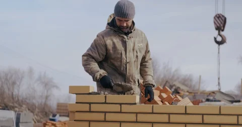 Bricklayer puts cement on brick. Professional builder beautifully lays brick. Stock Footage 128939081