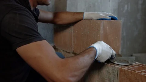 Bricklayer puts a trowel on a brick and takes the phone. Close-up. Slow-motion Video stock 73362048