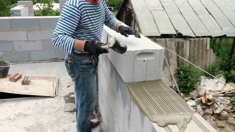 Bricklayer putting down another row of bricks in site Stock Footage 113399730