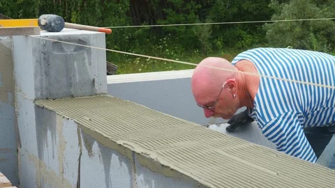 Bricklayer putting down another row of bricks in site Stock Footage 113402955
