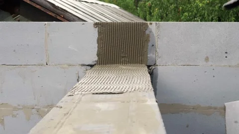 Bricklayer putting down another row of bricks in site Stock Footage 113404323