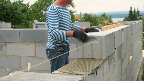 Bricklayer putting down another row of bricks in site Stock Footage 113414770
