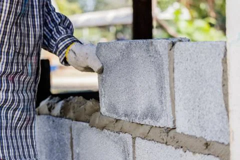 Bricklayer putting down another row of bricks in site Stock Photos