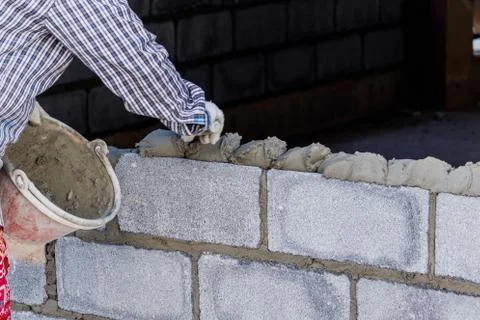 Bricklayer putting down another row of bricks in site Stock Photos