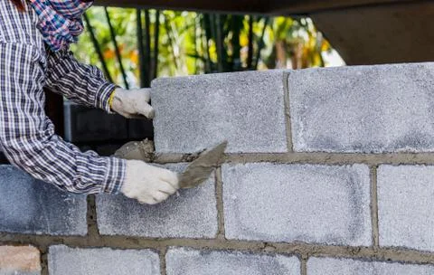Bricklayer putting down another row of bricks in site Stock Photos