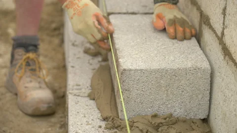 Bricklayer Secures Concrete Block On Mortar And Concrete Base Stock Footage 239755205