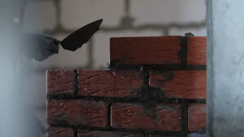 Bricklayer smoothing mortar on brick wall with trowel Stock Footage 323445401