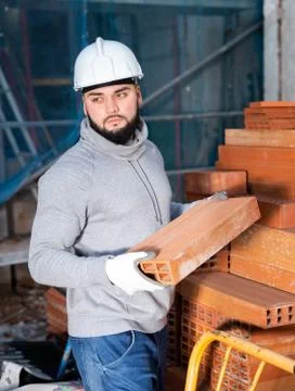 Bricklayer taking red bricks from stack Stock Photos