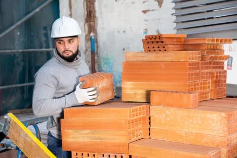 Bricklayer taking red bricks from stack Stock Photos